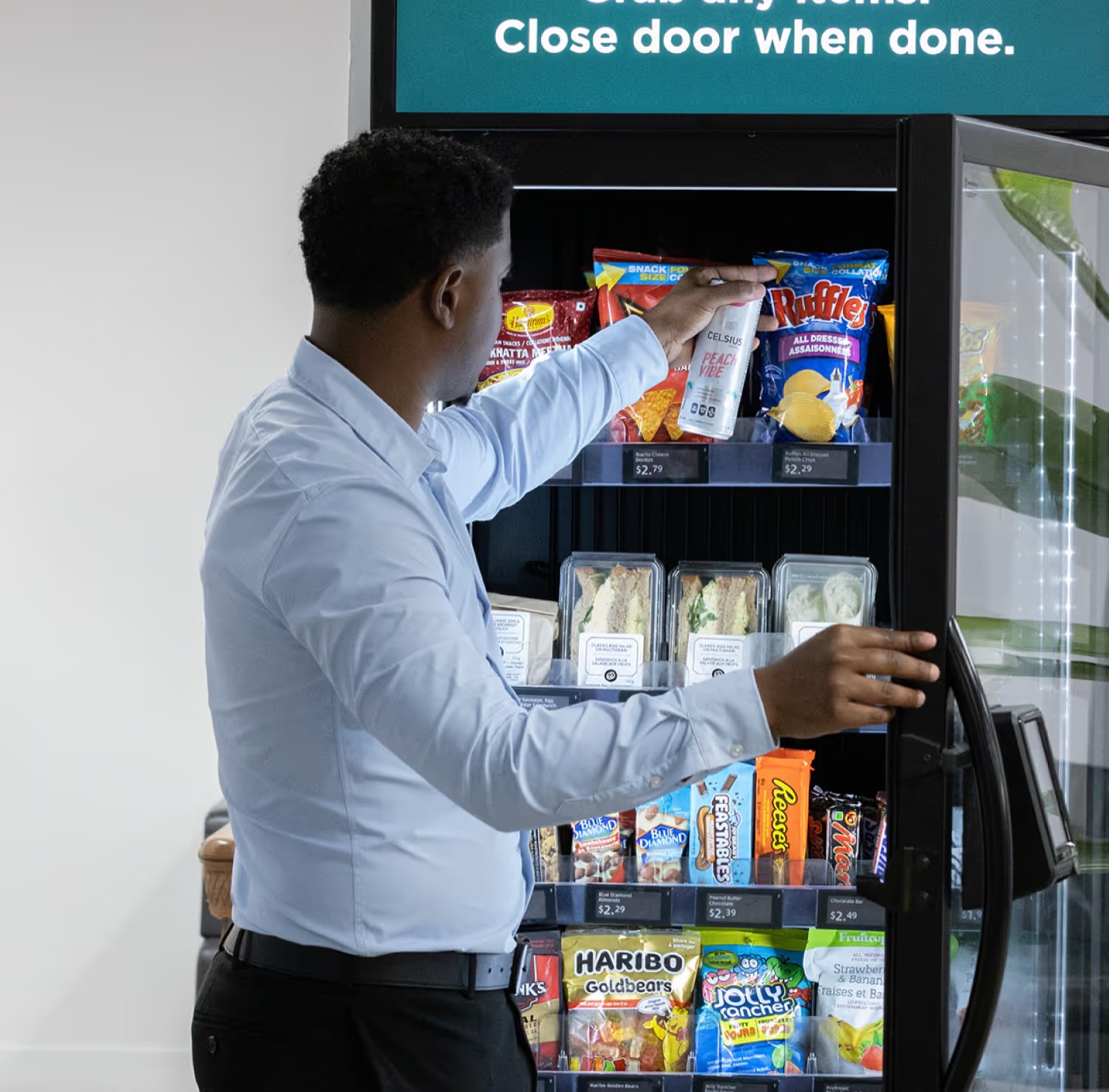 An operator restocking a glass-front combo vending machine with snacks and fresh food