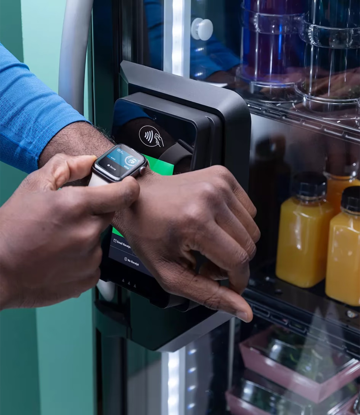 A customer paying by tap at a glass-front cooler placed in a high-traffic walkway